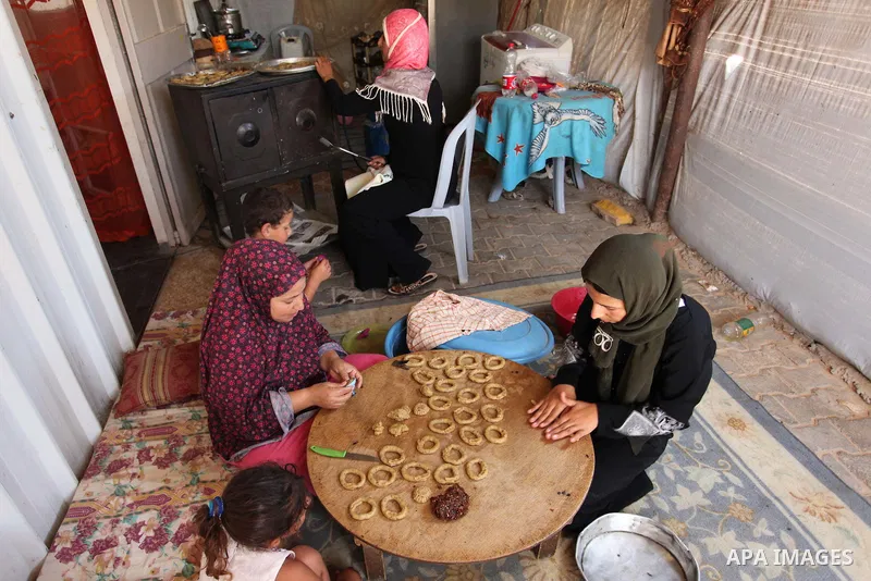A Palestinian family, whose house was destroeyed during 2014 war, make traditional cakes inside their makeshift shelter, ahead of Eid-al-Fitr celebrations in Khan Younis in the southern Gaza Strip July 3, 2016. Photo by...