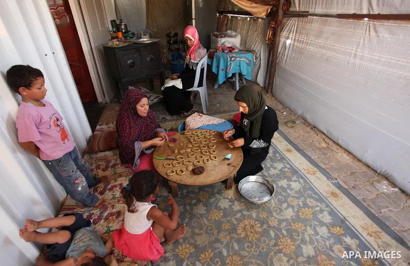A Palestinian family, whose house was destroeyed during 2014 war, make traditional cakes inside their makeshift shelter, ahead of Eid-al-Fitr celebrations in Khan Younis in the southern Gaza Strip July 3, 2016. Photo by...