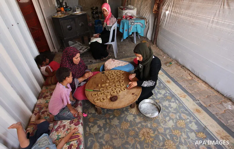 A Palestinian family, whose house was destroeyed during 2014 war, make traditional cakes inside their makeshift shelter, ahead of Eid-al-Fitr celebrations in Khan Younis in the southern Gaza Strip July 3, 2016. Photo by...