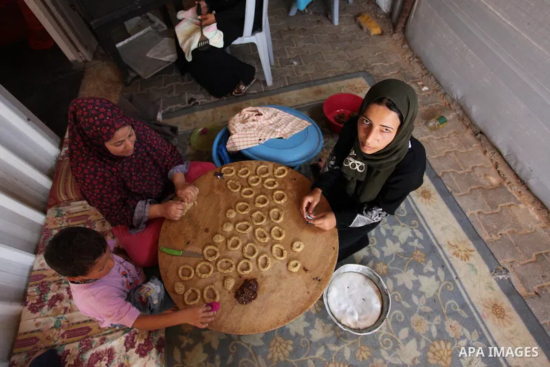 A Palestinian family, whose house was destroeyed during 2014 war, make traditional cakes inside their makeshift shelter, ahead of Eid-al-Fitr celebrations in Khan Younis in the southern Gaza Strip July 3, 2016. Photo by...