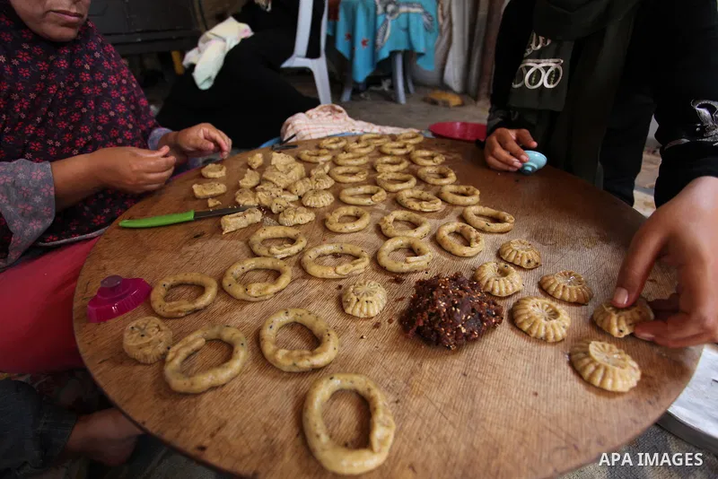 A Palestinian family, whose house was destroeyed during 2014 war, make traditional cakes inside their makeshift shelter, ahead of Eid-al-Fitr celebrations in Khan Younis in the southern Gaza Strip July 3, 2016. Photo by...