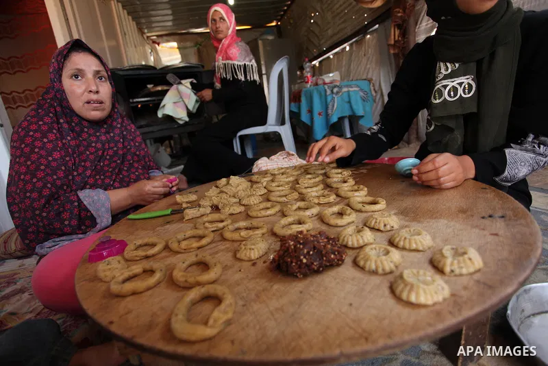 A Palestinian family, whose house was destroeyed during 2014 war, make traditional cakes inside their makeshift shelter, ahead of Eid-al-Fitr celebrations in Khan Younis in the southern Gaza Strip July 3, 2016. Photo by...