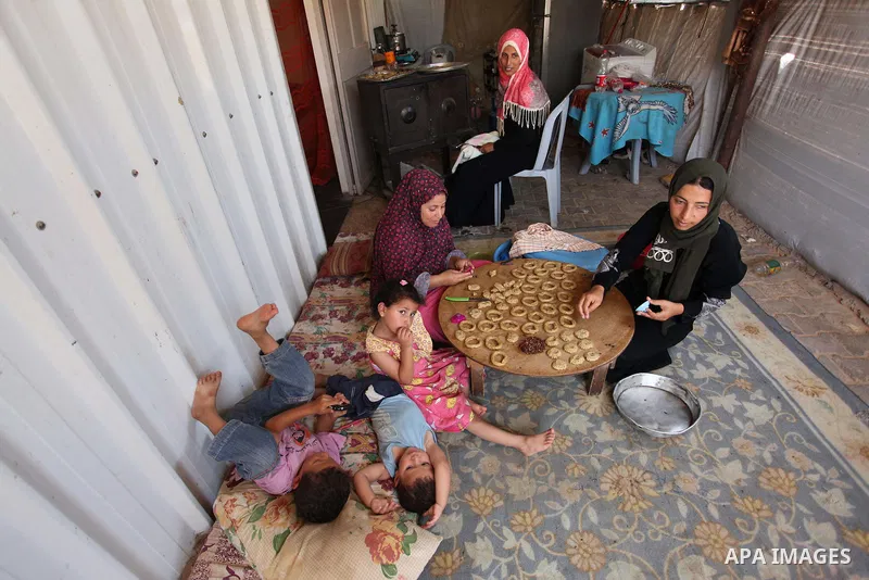 A Palestinian family, whose house was destroeyed during 2014 war, make traditional cakes inside their makeshift shelter, ahead of Eid-al-Fitr celebrations in Khan Younis in the southern Gaza Strip July 3, 2016. Photo by...