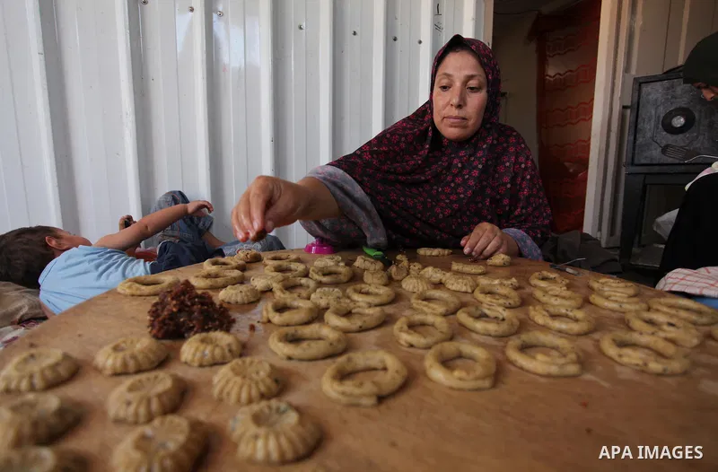 A Palestinian family, whose house was destroeyed during 2014 war, make traditional cakes inside their makeshift shelter, ahead of Eid-al-Fitr celebrations in Khan Younis in the southern Gaza Strip July 3, 2016. Photo by...