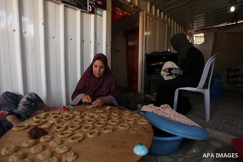 A Palestinian family, whose house was destroeyed during 2014 war, make traditional cakes inside their makeshift shelter, ahead of Eid-al-Fitr celebrations in Khan Younis in the southern Gaza Strip July 3, 2016. Photo by...