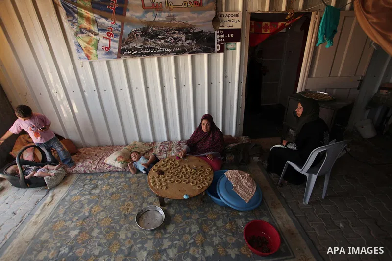 A Palestinian family, whose house was destroeyed during 2014 war, make traditional cakes inside their makeshift shelter, ahead of Eid-al-Fitr celebrations in Khan Younis in the southern Gaza Strip July 3, 2016. Photo by...