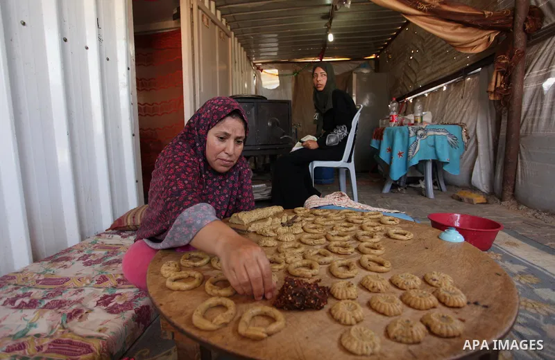 A Palestinian family, whose house was destroeyed during 2014 war, make traditional cakes inside their makeshift shelter, ahead of Eid-al-Fitr celebrations in Khan Younis in the southern Gaza Strip July 3, 2016. Photo by...
