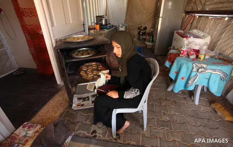 A Palestinian family, whose house was destroeyed during 2014 war, make traditional cakes inside their makeshift shelter, ahead of Eid-al-Fitr celebrations in Khan Younis in the southern Gaza Strip July 3, 2016. Photo by...