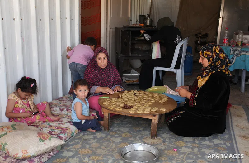 A Palestinian family, whose house was destroeyed during 2014 war, make traditional cakes inside their makeshift shelter, ahead of Eid-al-Fitr celebrations in Khan Younis in the southern Gaza Strip July 3, 2016. Photo by...