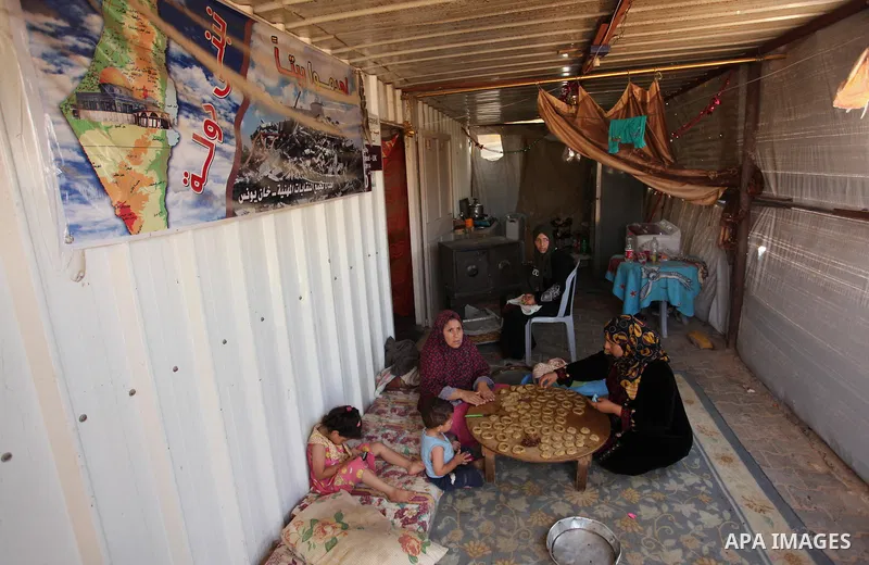 A Palestinian family, whose house was destroeyed during 2014 war, make traditional cakes inside their makeshift shelter, ahead of Eid-al-Fitr celebrations in Khan Younis in the southern Gaza Strip July 3, 2016. Photo by...