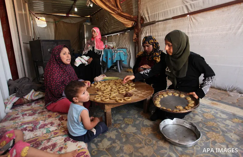 A Palestinian family, whose house was destroeyed during 2014 war, make traditional cakes inside their makeshift shelter, ahead of Eid-al-Fitr celebrations in Khan Younis in the southern Gaza Strip July 3, 2016. Photo by...