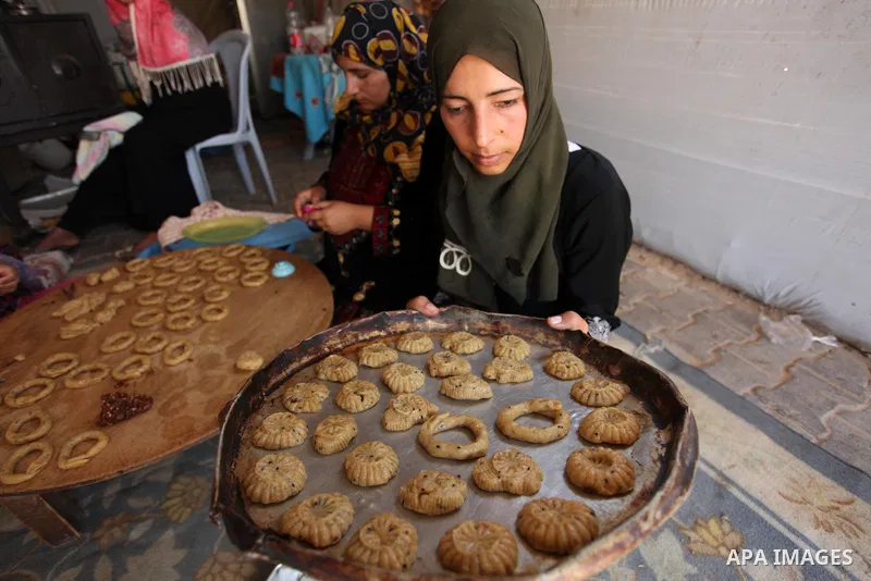 A Palestinian family, whose house was destroeyed during 2014 war, make traditional cakes inside their makeshift shelter, ahead of Eid-al-Fitr celebrations in Khan Younis in the southern Gaza Strip July 3, 2016. Photo by...