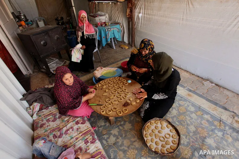 A Palestinian family, whose house was destroeyed during 2014 war, make traditional cakes inside their makeshift shelter, ahead of Eid-al-Fitr celebrations in Khan Younis in the southern Gaza Strip July 3, 2016. Photo by...