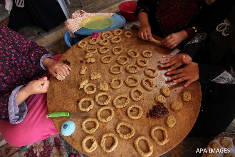 A Palestinian family, whose house was destroeyed during 2014 war, make traditional cakes inside their makeshift shelter, ahead of Eid-al-Fitr celebrations in Khan Younis in the southern Gaza Strip July 3, 2016. Photo by...