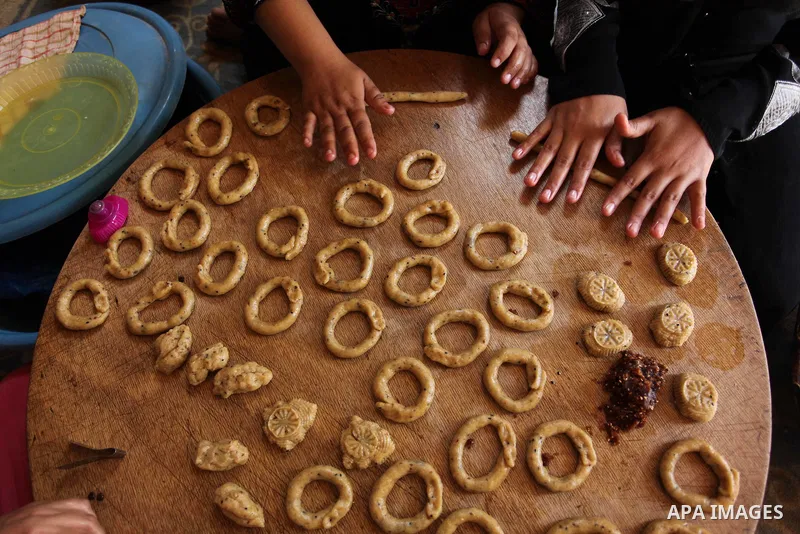 A Palestinian family, whose house was destroeyed during 2014 war, make traditional cakes inside their makeshift shelter, ahead of Eid-al-Fitr celebrations in Khan Younis in the southern Gaza Strip July 3, 2016. Photo by...