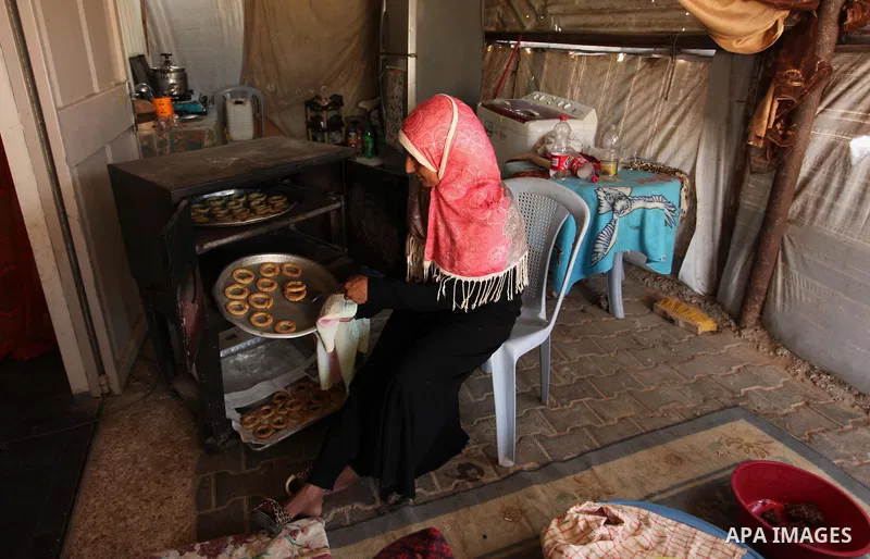 A Palestinian family, whose house was destroeyed during 2014 war, make traditional cakes inside their makeshift shelter, ahead of Eid-al-Fitr celebrations in Khan Younis in the southern Gaza Strip July 3, 2016. Photo by...