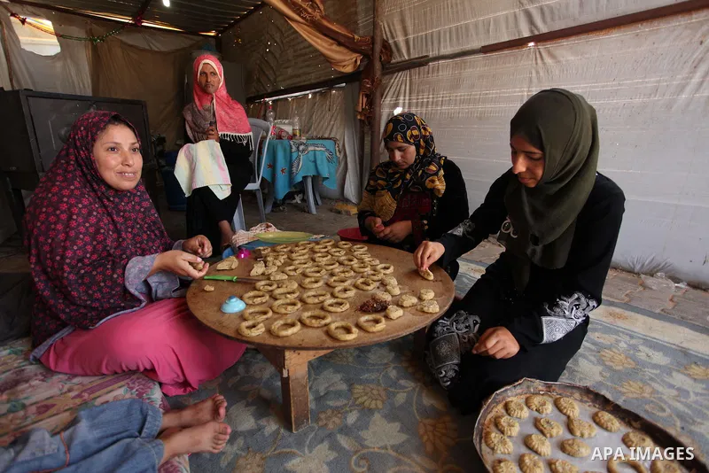 A Palestinian family, whose house was destroeyed during 2014 war, make traditional cakes inside their makeshift shelter, ahead of Eid-al-Fitr celebrations in Khan Younis in the southern Gaza Strip July 3, 2016. Photo by...