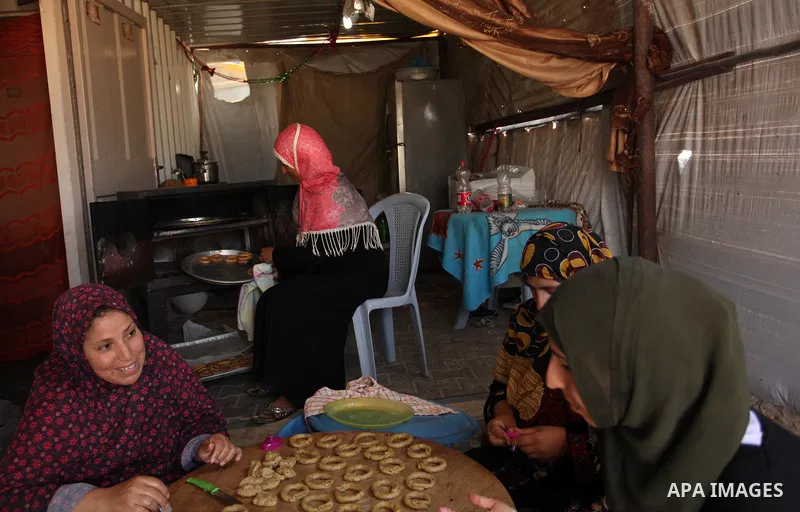 A Palestinian family, whose house was destroeyed during 2014 war, make traditional cakes inside their makeshift shelter, ahead of Eid-al-Fitr celebrations in Khan Younis in the southern Gaza Strip July 3, 2016. Photo by...