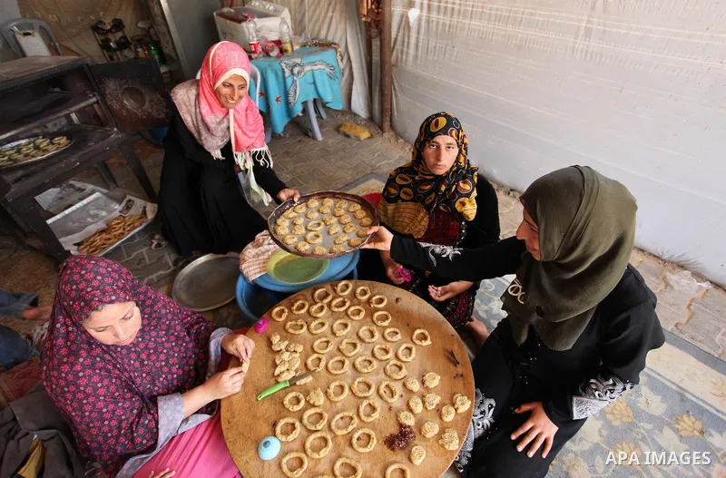 A Palestinian family, whose house was destroeyed during 2014 war, make traditional cakes inside their makeshift shelter, ahead of Eid-al-Fitr celebrations in Khan Younis in the southern Gaza Strip July 3, 2016. Photo by...