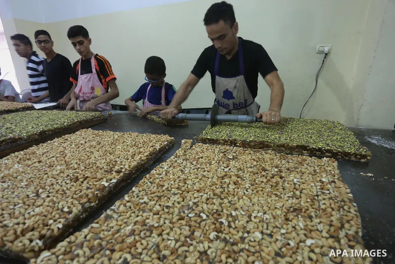 Palestinians prepare sweet known in Arabic as "Halkoum" ahead of the Eid al-Fitr holiday, in Gaza city, on July 3, 2016. Eid al-Fitr marks the end of Muslim's holy fasting month of Ramadan when faithfuls abstain from eat...