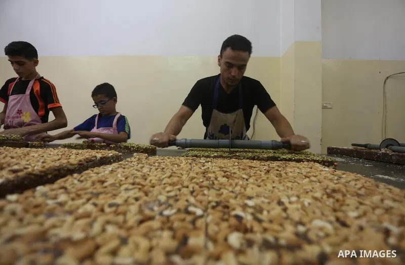 Palestinians prepare sweet known in Arabic as "Halkoum" ahead of the Eid al-Fitr holiday, in Gaza city, on July 3, 2016. Eid al-Fitr marks the end of Muslim's holy fasting month of Ramadan when faithfuls abstain from eat...