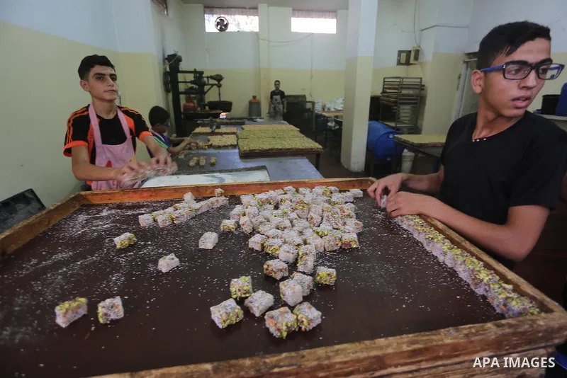 Palestinians prepare sweet known in Arabic as "Halkoum" ahead of the Eid al-Fitr holiday, in Gaza city, on July 3, 2016. Eid al-Fitr marks the end of Muslim's holy fasting month of Ramadan when faithfuls abstain from eat...