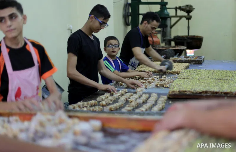 Palestinians prepare sweet known in Arabic as "Halkoum" ahead of the Eid al-Fitr holiday, in Gaza city, on July 3, 2016. Eid al-Fitr marks the end of Muslim's holy fasting month of Ramadan when faithfuls abstain from eat...