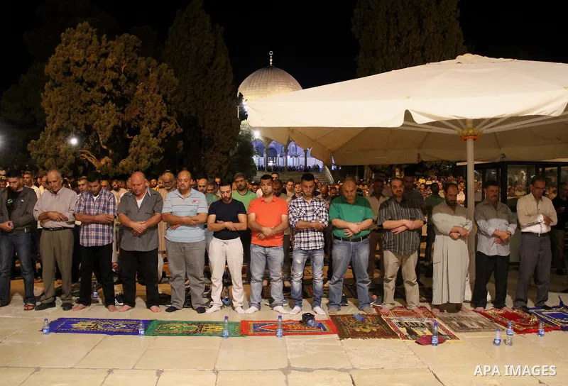 Palestinian Muslim worshippers perform "Taraweeh", nightly prayer of the month of Ramadan, in front of the Dome of the Rock mosque, in Jerusalem's old city on July 03, 2016. Photo by Mahfouz Abu Turk