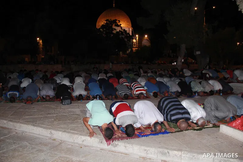 Palestinian Muslim worshippers perform "Taraweeh", nightly prayer of the month of Ramadan, in front of the Dome of the Rock mosque, in Jerusalem's old city on July 03, 2016. Photo by Mahfouz Abu Turk