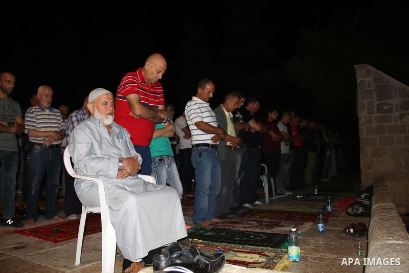 Palestinian Muslim worshippers perform "Taraweeh", nightly prayer of the month of Ramadan, in front of the Dome of the Rock mosque, in Jerusalem's old city on July 03, 2016. Photo by Mahfouz Abu Turk
