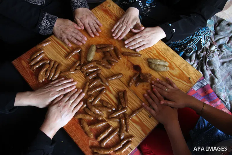 Palestinian women prepare date-filled mini cakes traditional for the Eid al-Fitr, a three-day holiday that marks the end of the fasting month of Ramadan, in Rafah in the southern Gaza Strip on July 4, 2016, as Muslims th...