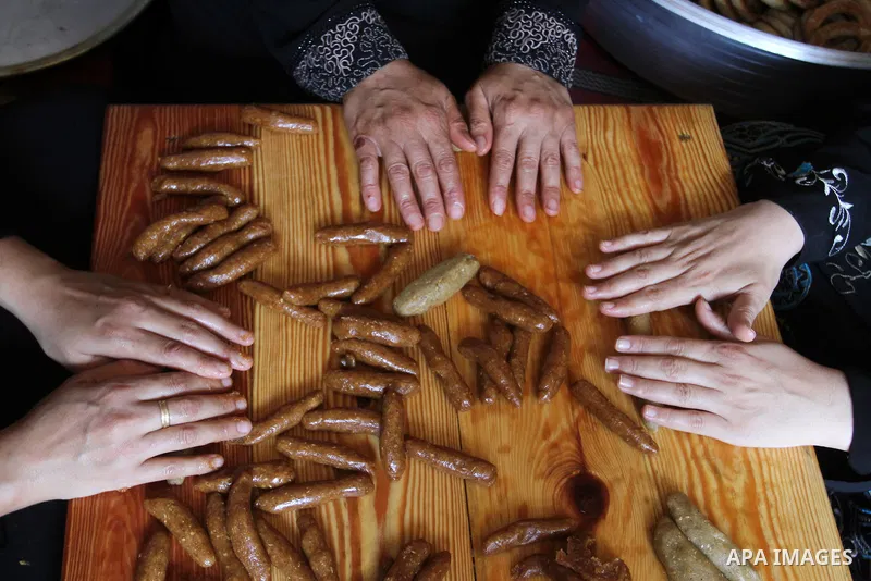 Palestinian women prepare date-filled mini cakes traditional for the Eid al-Fitr, a three-day holiday that marks the end of the fasting month of Ramadan, in Rafah in the southern Gaza Strip on July 4, 2016, as Muslims th...