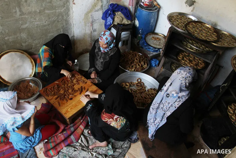 Palestinian women prepare date-filled mini cakes traditional for the Eid al-Fitr, a three-day holiday that marks the end of the fasting month of Ramadan, in Rafah in the southern Gaza Strip on July 4, 2016, as Muslims th...