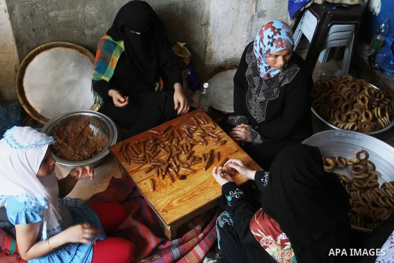 Palestinian women prepare date-filled mini cakes traditional for the Eid al-Fitr, a three-day holiday that marks the end of the fasting month of Ramadan, in Rafah in the southern Gaza Strip on July 4, 2016, as Muslims th...