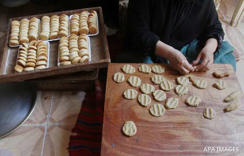 Palestinian women prepare date-filled mini cakes traditional for the Eid al-Fitr, a three-day holiday that marks the end of the fasting month of Ramadan, in Rafah in the southern Gaza Strip on July 4, 2016, as Muslims th...