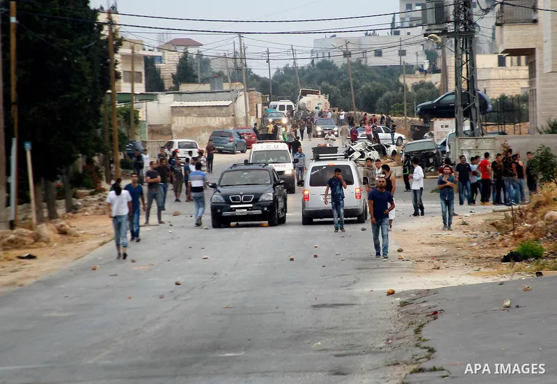 Masked Palestinian men collect stones during clashes between Palestinian protesters and Israeli security forces in the village of Dura near the Israeli occupied West Bank city of Hebron, July 4, 2016. Israeli troops lock...