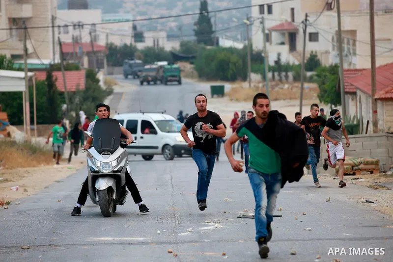 Masked Palestinian men collect stones during clashes between Palestinian protesters and Israeli security forces in the village of Dura near the Israeli occupied West Bank city of Hebron, July 4, 2016. Israeli troops lock...