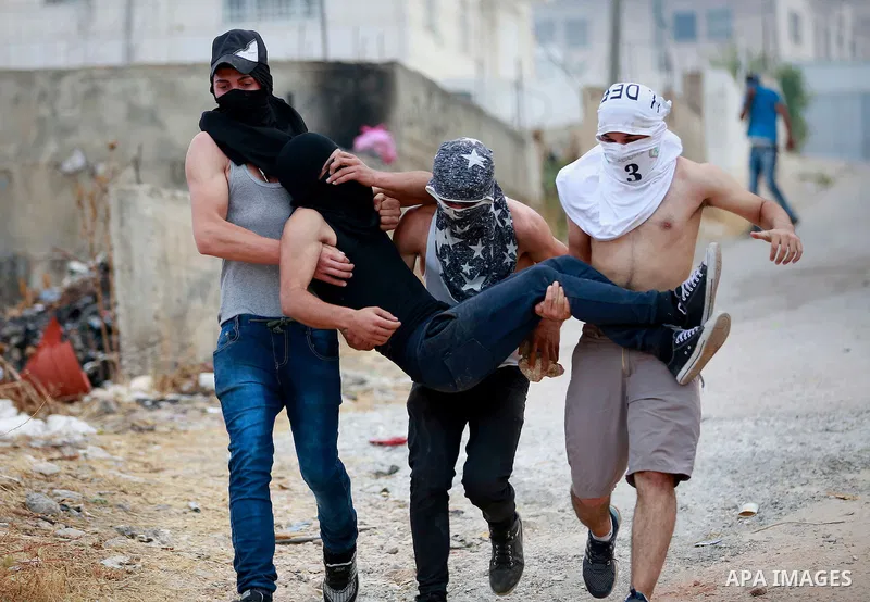 Masked Palestinian men carry a comrade during clashes between Palestinian protesters and Israeli security forces in the village of Dura near the Israeli occupied West Bank city of Hebron, July 4, 2016. Israeli troops loc...