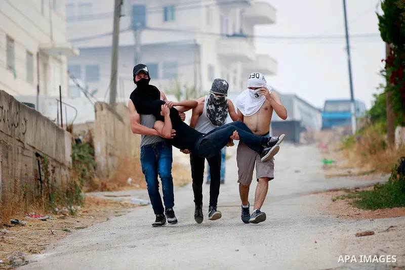 Masked Palestinian men carry a comrade during clashes between Palestinian protesters and Israeli security forces in the village of Dura near the Israeli occupied West Bank city of Hebron, July 4, 2016. Israeli troops loc...