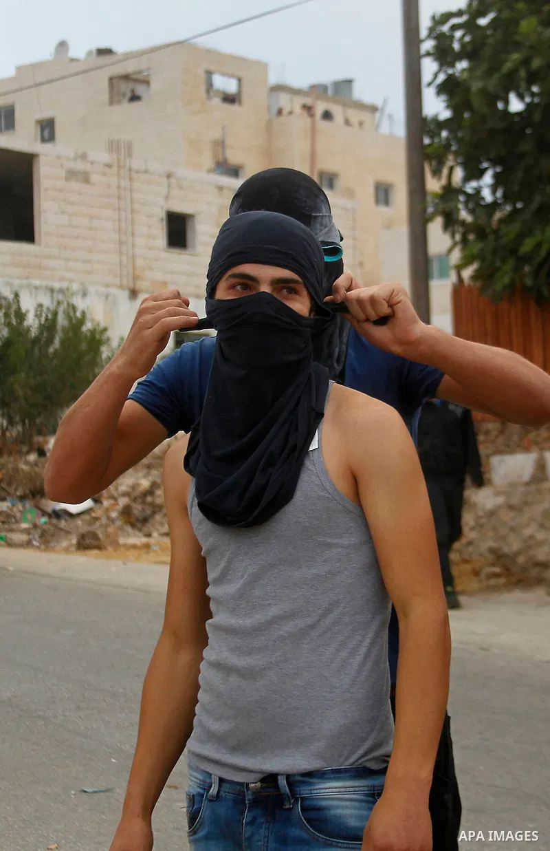 Masked Palestinian men collect stones during clashes between Palestinian protesters and Israeli security forces in the village of Dura near the Israeli occupied West Bank city of Hebron, July 4, 2016. Israeli troops lock...