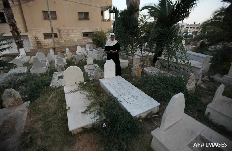 Palestinian women visit the graves of relatives at a cemetery on the first day of Eid al-Fitr celebrations, which marks the end of the holy fasting month of Ramadan, in the West Bank city of Nablus, on July 6, 2016. Phot...