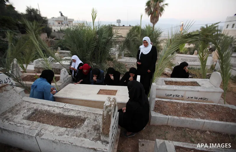 Palestinian women visit the graves of relatives at a cemetery on the first day of Eid al-Fitr celebrations, which marks the end of the holy fasting month of Ramadan, in the West Bank city of Nablus, on July 6, 2016. Phot...