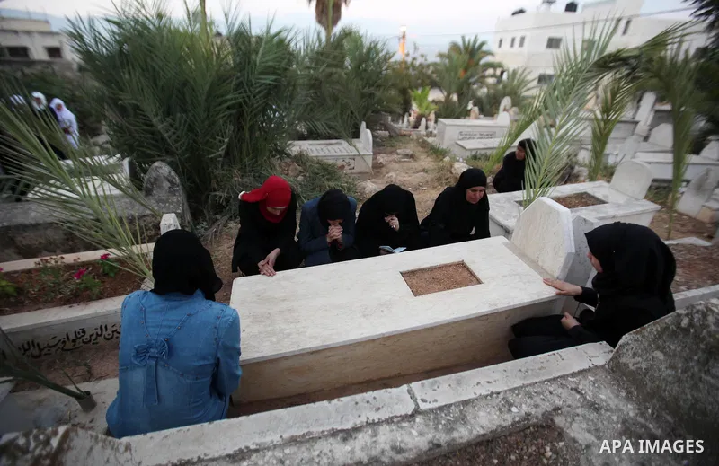 Palestinian women visit the graves of relatives at a cemetery on the first day of Eid al-Fitr celebrations, which marks the end of the holy fasting month of Ramadan, in the West Bank city of Nablus, on July 6, 2016. Phot...