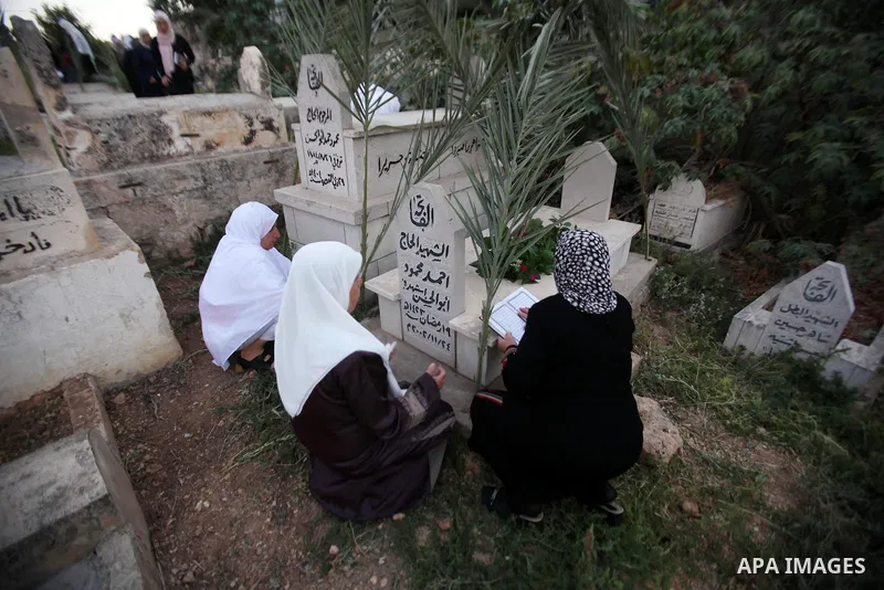 Palestinian women visit the graves of relatives at a cemetery on the first day of Eid al-Fitr celebrations, which marks the end of the holy fasting month of Ramadan, in the West Bank city of Nablus, on July 6, 2016. Phot...