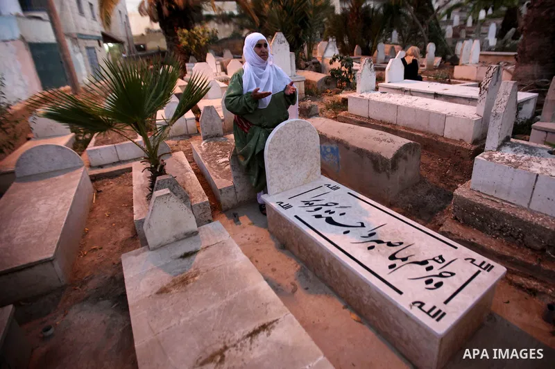 Palestinian women visit the graves of relatives at a cemetery on the first day of Eid al-Fitr celebrations, which marks the end of the holy fasting month of Ramadan, in the West Bank city of Nablus, on July 6, 2016. Phot...