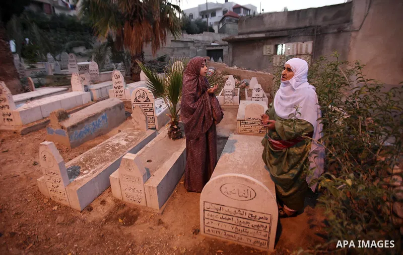 Palestinian women visit the graves of relatives at a cemetery on the first day of Eid al-Fitr celebrations, which marks the end of the holy fasting month of Ramadan, in the West Bank city of Nablus, on July 6, 2016. Phot...