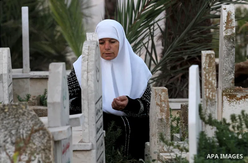 Palestinian women visit the graves of relatives at a cemetery on the first day of Eid al-Fitr celebrations, which marks the end of the holy fasting month of Ramadan, in the West Bank city of Nablus, on July 6, 2016. Phot...