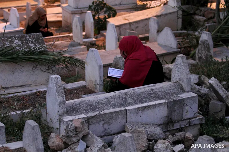 Palestinian women visit the graves of relatives at a cemetery on the first day of Eid al-Fitr celebrations, which marks the end of the holy fasting month of Ramadan, in the West Bank city of Nablus, on July 6, 2016. Phot...