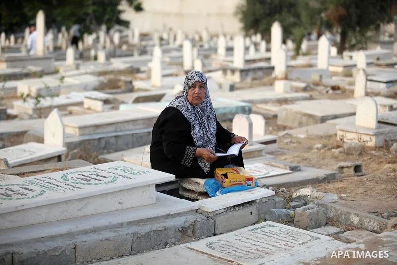 A Palestinian woman reads the Koran next to the grave of her relative at a cemetery on the first day of Eid al-Fitr celebrations, which marks the end of the holy fasting month of Ramadan, in Gaza City July 6, 2016. Photo...