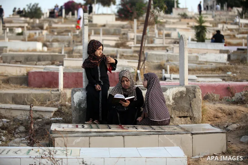 A Palestinian woman reads the Koran next to the grave of her relative at a cemetery on the first day of Eid al-Fitr celebrations, which marks the end of the holy fasting month of Ramadan, in Gaza City July 6, 2016. Photo...